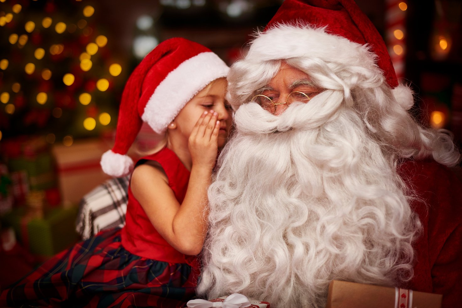 A photo of a child whispering to Santa